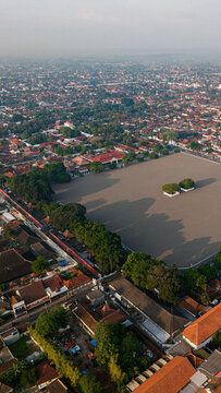 Aerial view of Alun-Alun Utara's vast sandy expanse contrasts with the dense urban fabric, a tranquil void amid Yogyakarta's vibrant tapestry, Yogyakarta, Daerah Istimewa Yogyakarta, Indonesia.