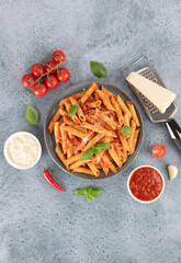 Italian pasta penne arrabiata with tomato sauce, chili pepper on blue background.Top view.Copy space