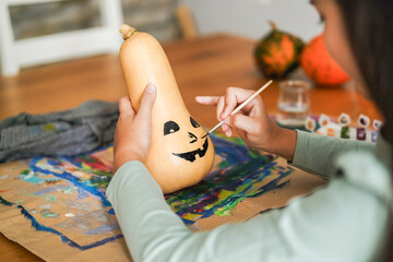 Female kid painting a pumpkin for an halloween party fest - Holidays, education and art concept - Main focus on right hand