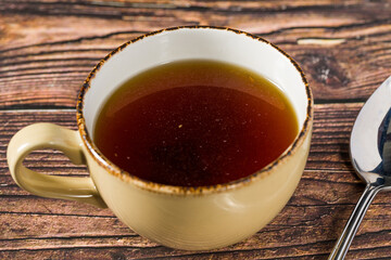 Hot consomme beef tail served in ceramic cup on rustic wooden table