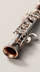 Naklejka premium A detailed macro shot of a vintage clarinet focusing on its intricate silver keys and the dark wood grain. The instrument rests on a plain, neutral surface, highlighting its craftsmanship.