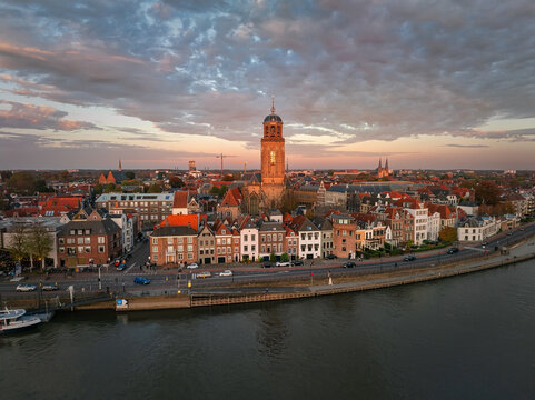 Aerial view of the Lebuinus Church towering over the old town along the tranquil IJssel River under a pastel sky, Deventer, Overijssel, Netherlands.