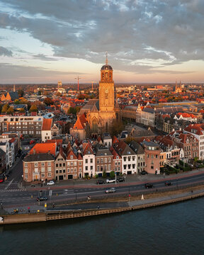 Aerial view of the Lebuinus Church standing tall amidst the quaint rooftops, a majestic monument against the softly illuminated sky, Deventer, Overijssel, Netherlands.