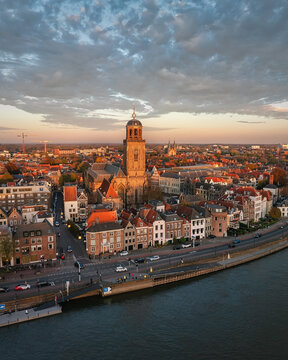 Aerial view of the Lebuinus Church standing tall amidst the rooftops, bathed in the warm glow of the setting sun, Deventer, Overijssel, Netherlands.