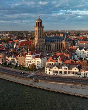 Aerial view of the majestic Lebuinus Church rises above the rooftops of a historic city, its spire piercing the cloudy sky, Deventer, Overijssel, Netherlands.