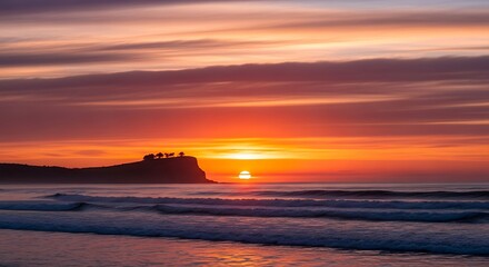Vibrant orange sunset over the ocean with a silhouetted cliff.
