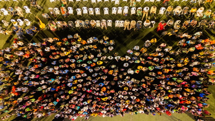 Aerial view of a gathering of people, some seated in white chairs, under a blanket of light, creating a mesmerizing contrast of shadows, Port Harcourt, Port Harcourt, Nigeria.