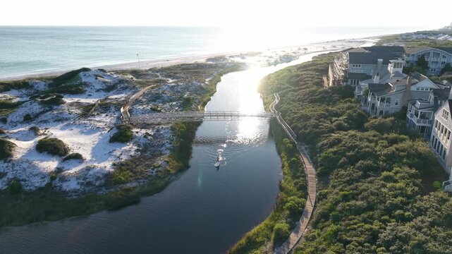 Vertically tilted up drone movement at coastal lagoon meeting the ocean water at bright sunshine, 30A, Florida, USA