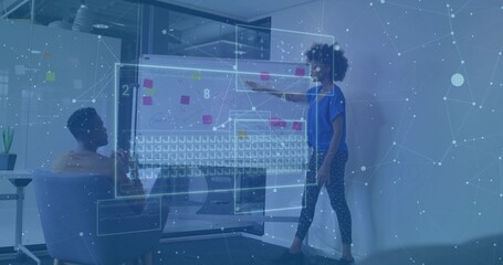 Colleagues collaborating around translucent interface in office space, repositioning sticky-note