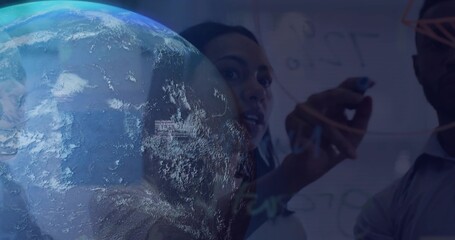 Three professionals sketching diagrams with markers on glass board in office, with Earth hologram