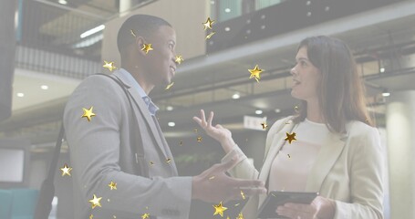 Discussing two professionals reviewing project on tablet in office atrium, golden star overlays