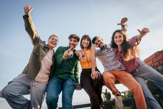 Portrait of a happy non-binary person smiling on the beach at sunset. Concept of gen z queer joy, lgbtqia+ pride, gender identity, self-love and authentic representation in nature.