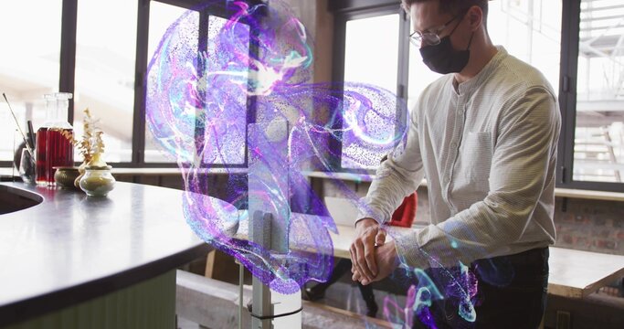 Sanitizing masked man placing hands under sanitizer dispenser at wooden counter, copy space - Powered by Adobe