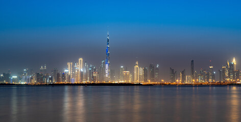 Dubai skyline glows at twilight over calm waters