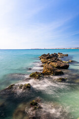 Turquoise water flows around mossy rocks