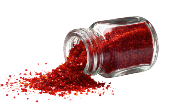 Red spice spills from a small, clear glass jar