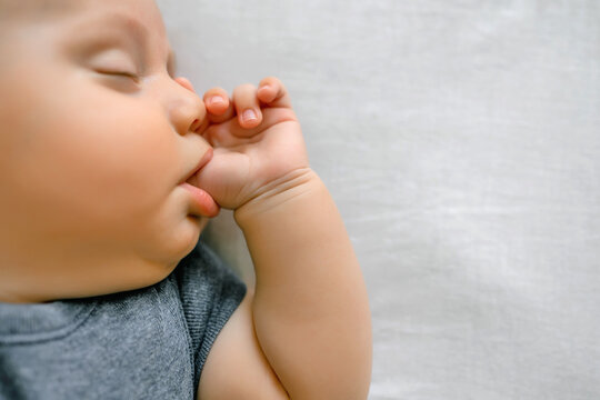 Adorable baby sucking thumb on the bed