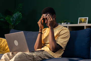 Young man experiencing headache while working from home