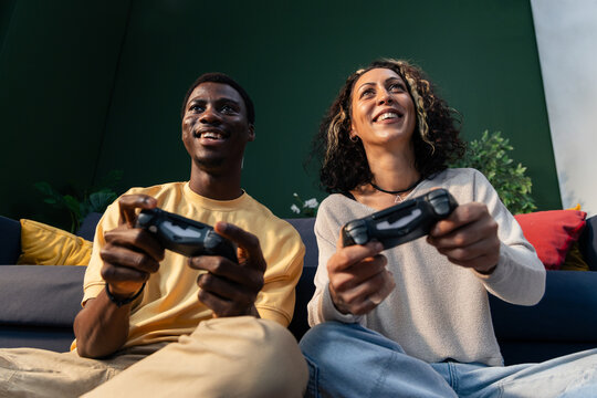 Diverse couple playing video game with controllers smiling - Powered by Adobe