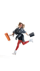 Joyful woman in plaid outfit and white boots holding shopping bags in dynamic motion. Concept of contemporary retail lifestyle, elegance, and energy in modern fashion promotion.