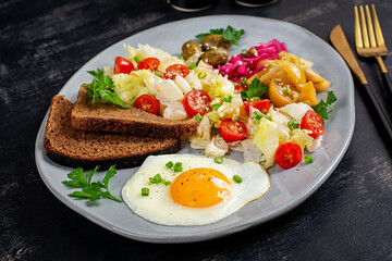 Healthy vegetarian breakfast. Fried egg, whole grain bread, and a vegetable salad.