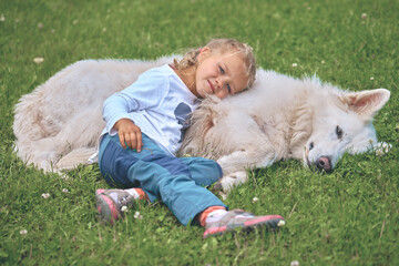 Four years old girl portrayed with her swiss white shepherd friend