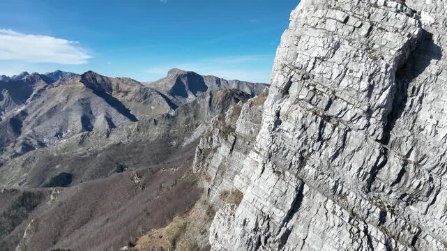 Aerial view of rocky wall mountain peaks near Levigliani, contrasting with the sparse vegetation and clear blue sky, Levigliani, Toscana, Italy.