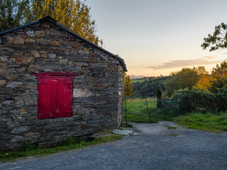 Stone houses in the mountains of A Fonsagrada, Lugo, Galicia, Spain. Traditional Galician mountain village with stone walls wooden details and black slate roofs on a sunny day in northern Spain.