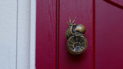 An elegant door handle. A snail-shaped door handle on a red background.