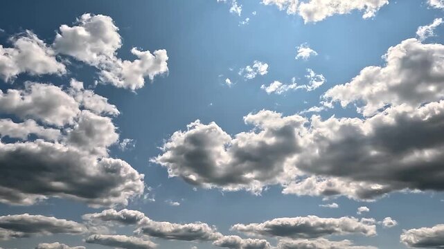 Flowing rainy clouds in the blue skies. 4K video (Ultra High Definition) of cloudscape. Sky and clouds Timelapse. Sun shines through the dramatic clouds on the blue sky background.