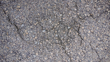 Close-Up of Rough Asphalt Texture Background: Gray Pavement Surface with Gravel and Small Cracks for Gritty Urban Design