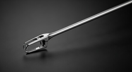 Close up of a surgical needle holder instrument on a dark background.