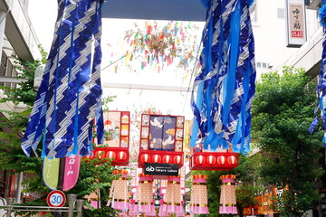 青と白を基調とした巨大な七夕飾りが商店街の上空を覆いつくし賑やかな夏の祭りの雰囲気を伝える写真です
