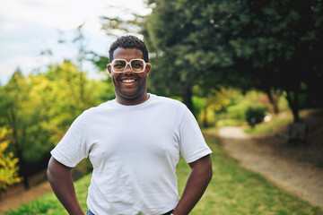 Smiling man standing outdoors on park path on sunny day