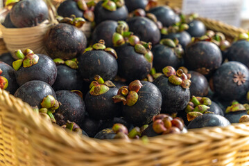 Woven basket filled with ripe mangosteens displayed at tropical street market