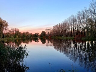 autumn trees silhouettes reflection on the still lake surface, twilights time, natural sky colors after the sunset