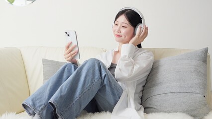 ワイヤレスヘッドフォンで音楽を聞くアジア人女性