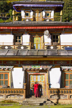Monk approaches ornate colorful temple doors