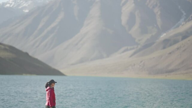 Indian woman near Chandratal Lake wearing red jacket, minimal travel composition showing balance between human and nature.