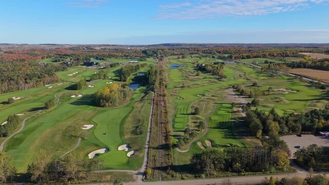 A wide, high-altitude aerial view of the TPC Toronto at Osprey Valley golf course, showcasing its unique layout famously bisected by a straight railway line.