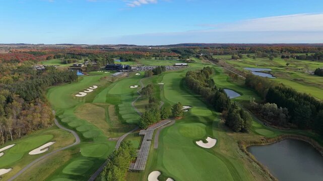 A stunning aerial view of the TPC Toronto at Osprey Valley golf course, showcasing the immaculate, rolling fairways and pristine white sand bunkers, all framed by vibrant autumn colours.