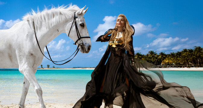 Powerful fashion woman in black sheer dress and gold metallic corset styling with pinto horse on tropical beach in Mauritius - Powered by Adobe