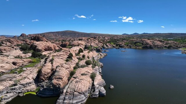 Aerial view of Willow Creek Reservoir, where the dark blue water contrasts with the light brown rock formations, creating a serene landscape, Willow Creek, Arizona, United States.