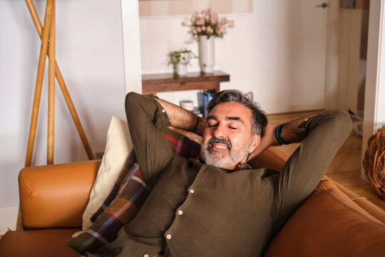 Man relaxing on sofa at home with tranquil expression