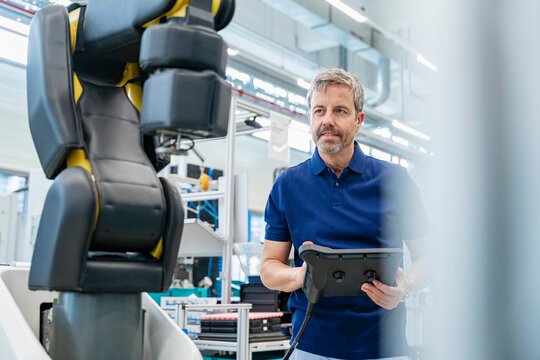 Engineer operating industrial robot in modern automated factory