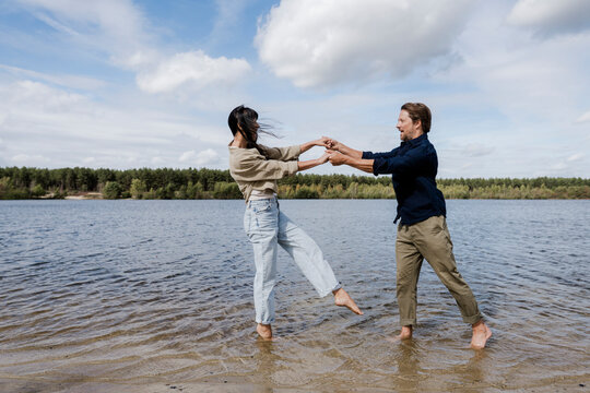 Couple dancing together outdoors by the lake on a windy day
