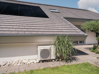 Modern house with solar panels and thermal heat pump outdoors in summer