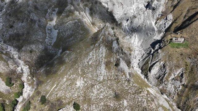 Aerial view of mountain peaks and structures creating a compelling contrast between the natural landscape and man-made elements, Tuscany, Italy.