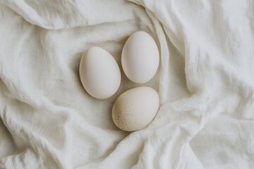 Three natural eggs resting on white textured fabric background