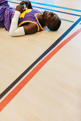 Exhausted basketball player lying on the court laughing after an intense game